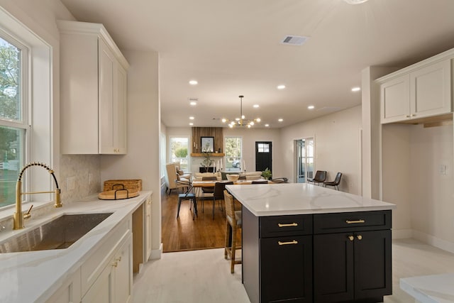 kitchen featuring white cabinetry, a healthy amount of sunlight, sink, and a kitchen island