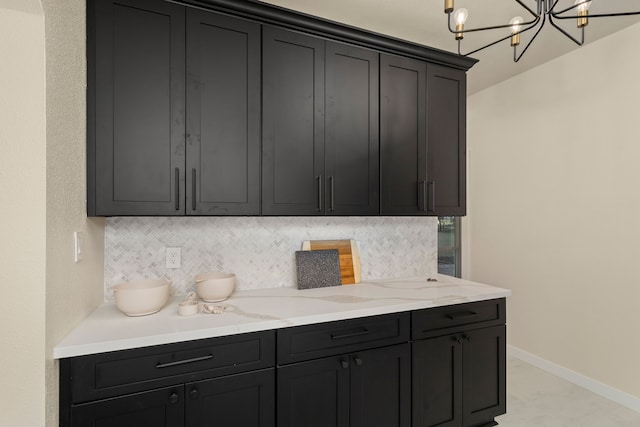 kitchen featuring an inviting chandelier, light stone countertops, and decorative backsplash