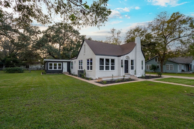 back house at dusk featuring a lawn and central AC