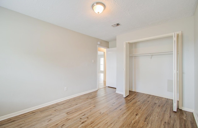 unfurnished bedroom featuring a closet, a textured ceiling, and light hardwood / wood-style flooring