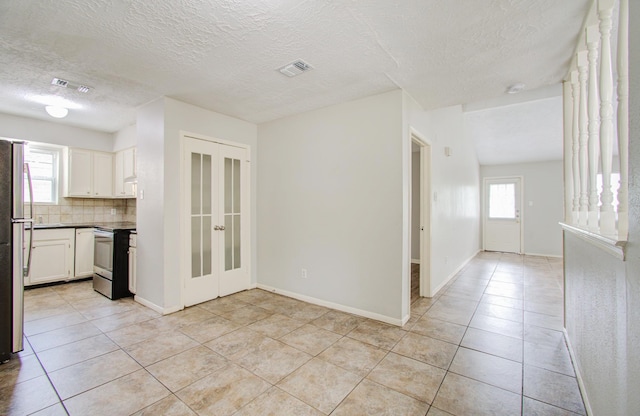 kitchen with white cabinets, light tile patterned flooring, stainless steel appliances, and tasteful backsplash