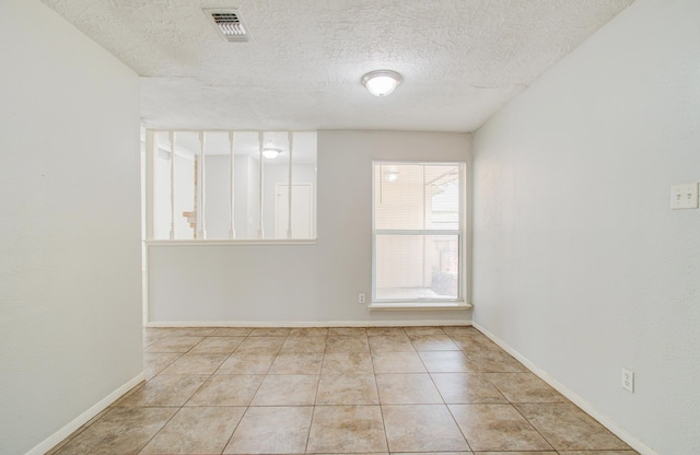 tiled empty room with a textured ceiling