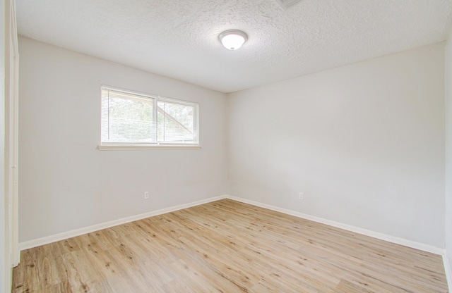 spare room featuring a textured ceiling and light hardwood / wood-style flooring