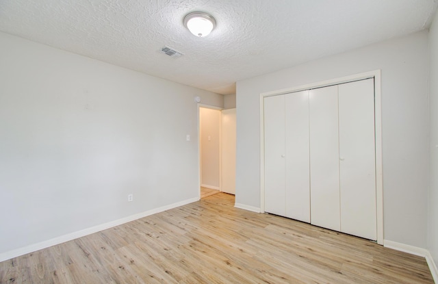 unfurnished bedroom with a textured ceiling, light hardwood / wood-style flooring, and a closet