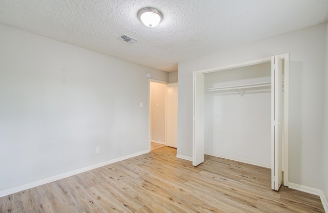 unfurnished bedroom featuring a closet, a textured ceiling, and light wood-type flooring