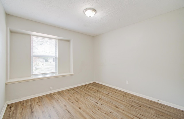 empty room with light hardwood / wood-style flooring and a textured ceiling