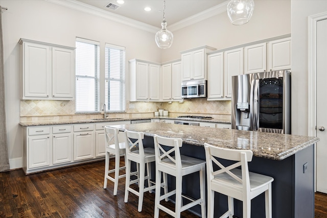 kitchen featuring white cabinets, stainless steel appliances, a center island, and dark hardwood / wood-style flooring