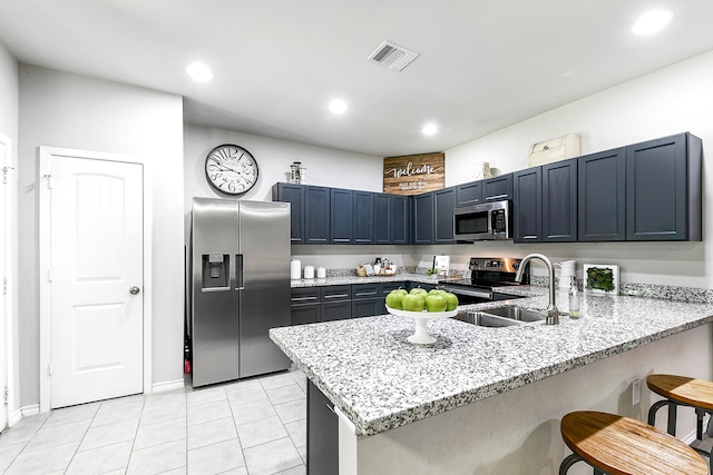 kitchen with light stone counters, appliances with stainless steel finishes, sink, a breakfast bar, and kitchen peninsula