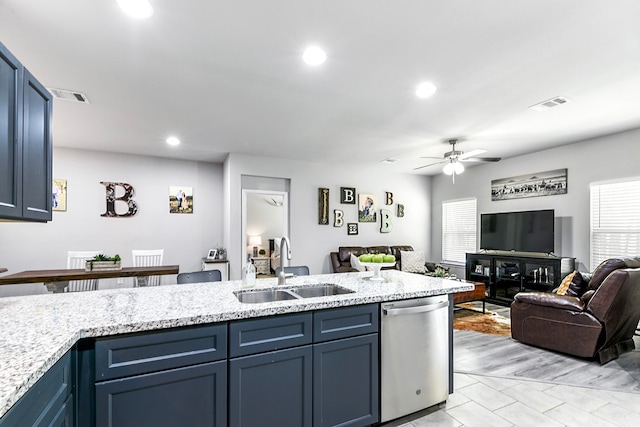 kitchen with sink, light stone countertops, ceiling fan, blue cabinets, and dishwasher