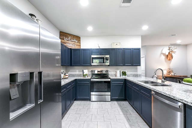 kitchen with blue cabinets, sink, light stone countertops, and stainless steel appliances