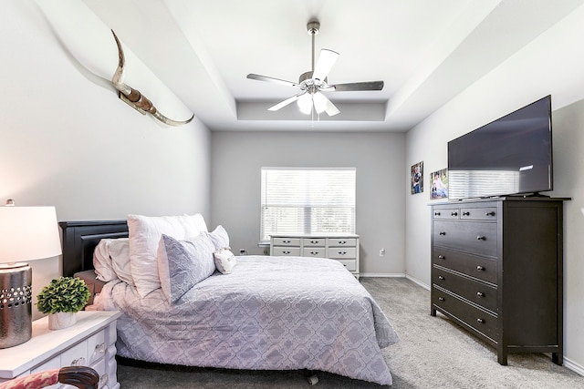 bedroom featuring ceiling fan, light carpet, and a tray ceiling