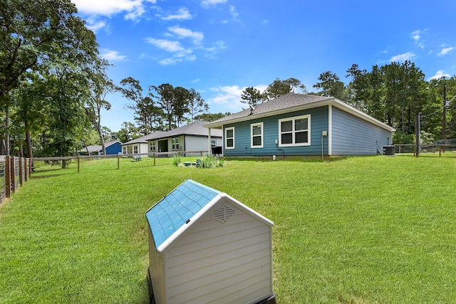 rear view of house with central AC and a yard