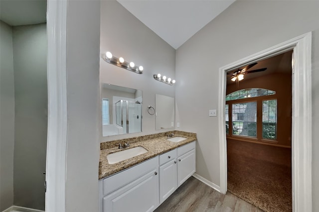 bathroom featuring a shower with door, ceiling fan, wood-type flooring, vanity, and lofted ceiling