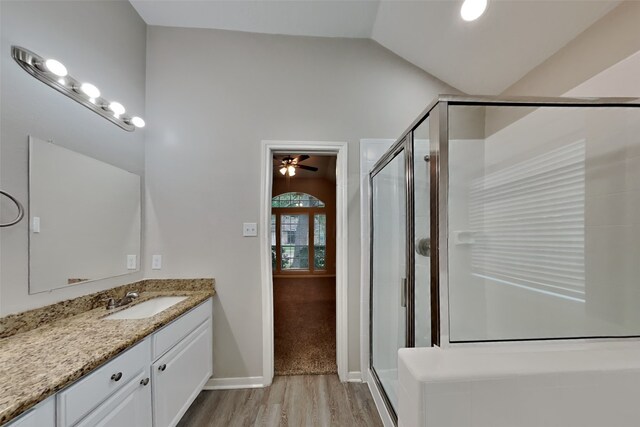 bathroom with walk in shower, hardwood / wood-style floors, lofted ceiling, and vanity