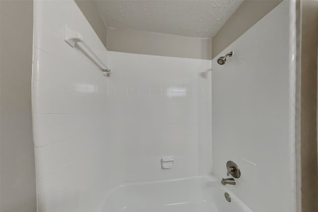 bathroom featuring tiled shower / bath combo and a textured ceiling