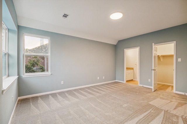 unfurnished bedroom with visible vents, light carpet, baseboards, and a spacious closet