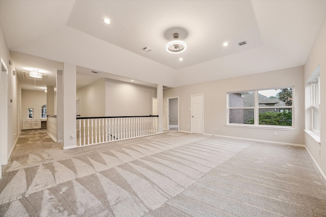 unfurnished room featuring light colored carpet, visible vents, baseboards, a raised ceiling, and attic access