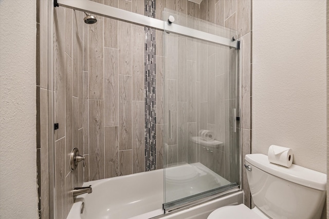 full bath featuring toilet, enclosed tub / shower combo, and a textured wall