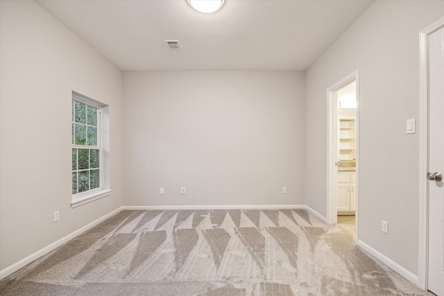 spare room with light carpet, visible vents, and baseboards