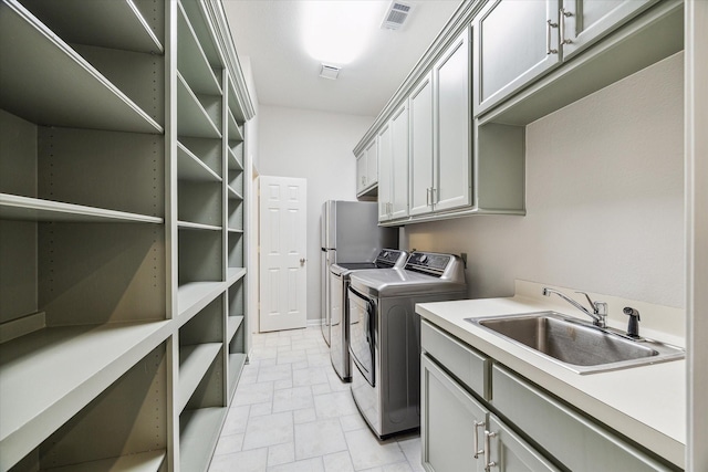 laundry room with cabinet space, independent washer and dryer, visible vents, and a sink