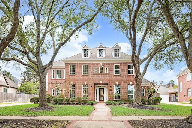 georgian-style home with a front yard, brick siding, and fence