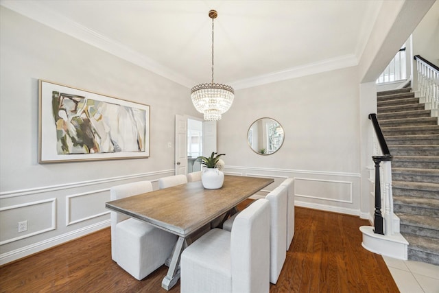 dining space featuring dark wood-style floors, stairway, ornamental molding, an inviting chandelier, and a decorative wall