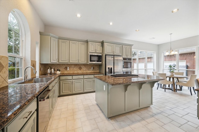 kitchen with stainless steel appliances, dark stone countertops, a sink, and pendant lighting