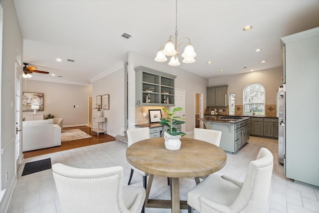 dining area featuring recessed lighting, baseboards, visible vents, ornamental molding, and ceiling fan with notable chandelier