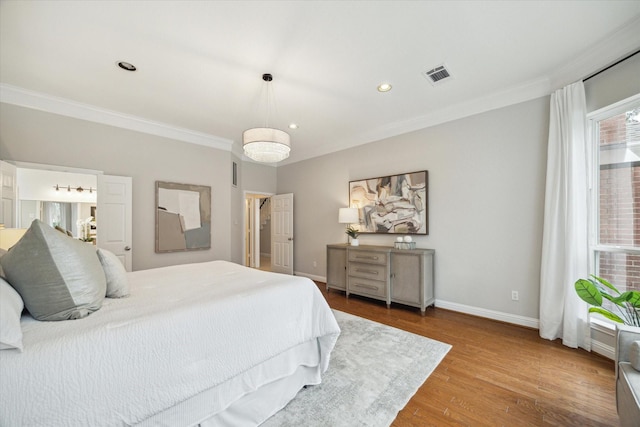 bedroom featuring crown molding, wood finished floors, visible vents, and baseboards