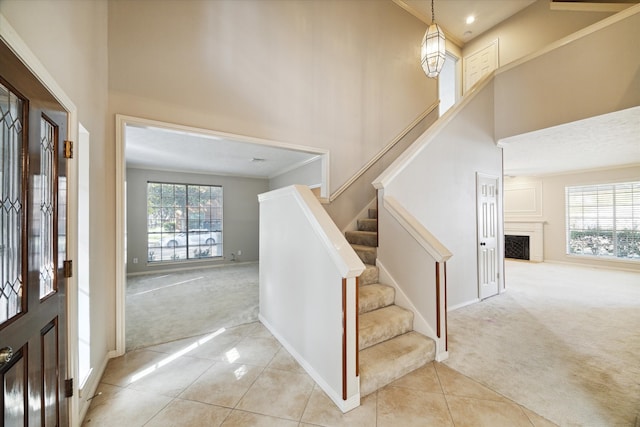 carpeted entryway featuring crown molding and a towering ceiling