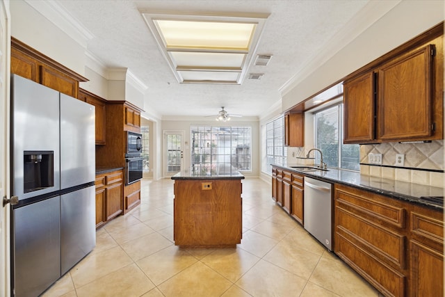 kitchen with a textured ceiling, appliances with stainless steel finishes, sink, and a center island