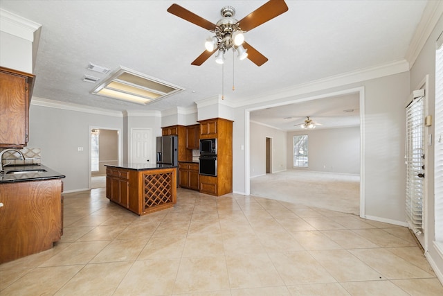 kitchen featuring black appliances, a kitchen island, a wealth of natural light, and ornamental molding