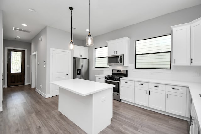 kitchen with stainless steel appliances, light hardwood / wood-style floors, white cabinets, and a kitchen island