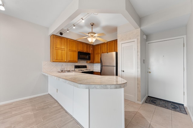 kitchen with kitchen peninsula, tasteful backsplash, rail lighting, stainless steel fridge, and white stove