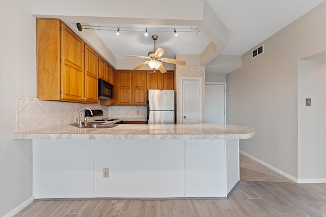 kitchen with kitchen peninsula, appliances with stainless steel finishes, sink, and backsplash