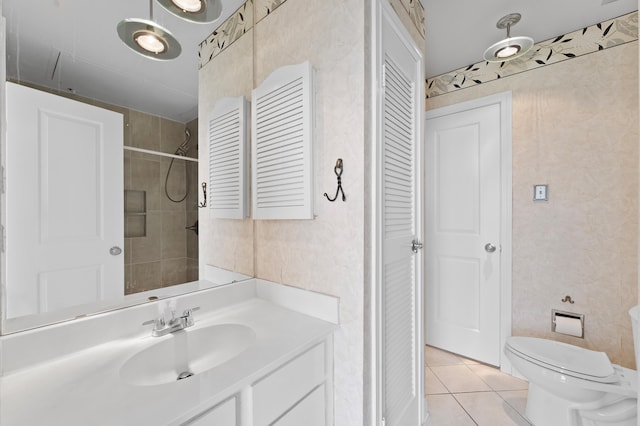 bathroom with vanity, tile patterned flooring, toilet, and a tile shower