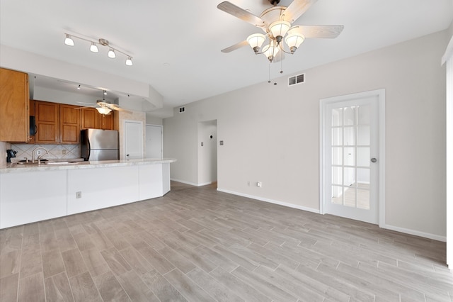 unfurnished living room featuring ceiling fan, sink, and light hardwood / wood-style flooring