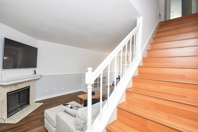 stairway with wood-type flooring and a premium fireplace