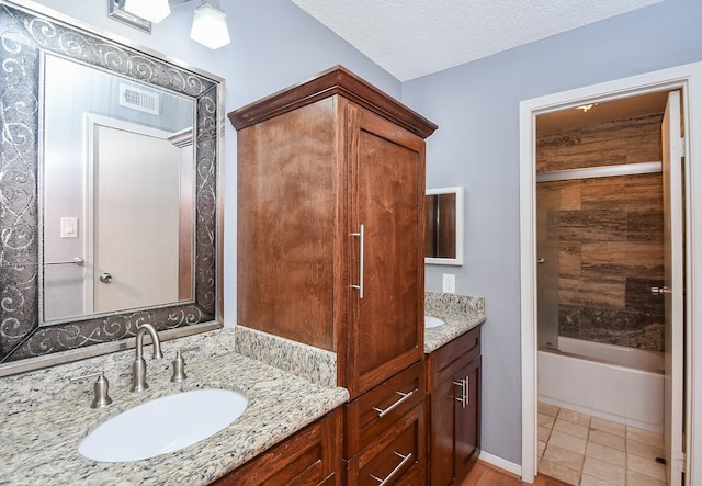 bathroom featuring tile patterned flooring, vanity, a textured ceiling, and tub / shower combination