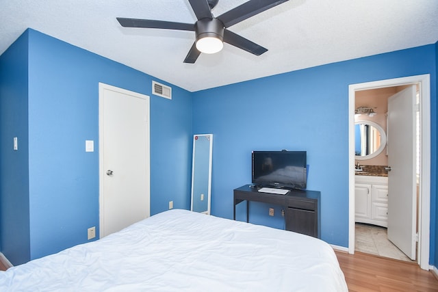 bedroom with light wood-type flooring, ensuite bath, ceiling fan, and sink