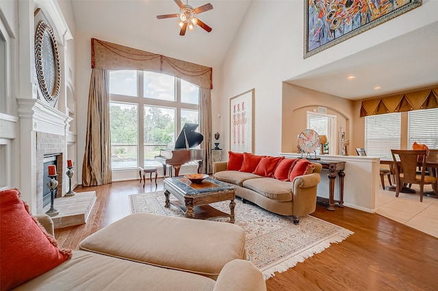 living room featuring hardwood / wood-style floors, ceiling fan, a fireplace, and high vaulted ceiling