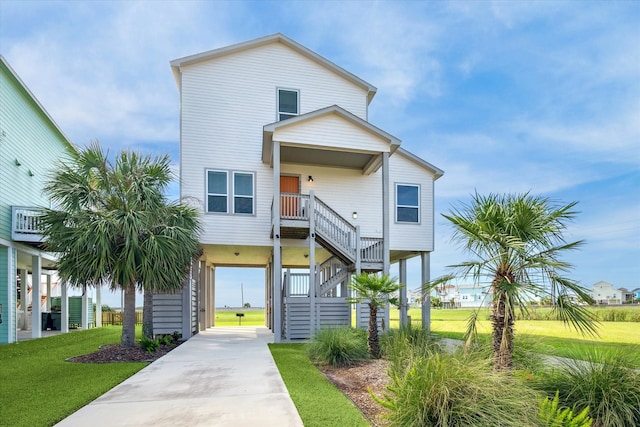 beach home featuring a porch, a carport, and a front yard