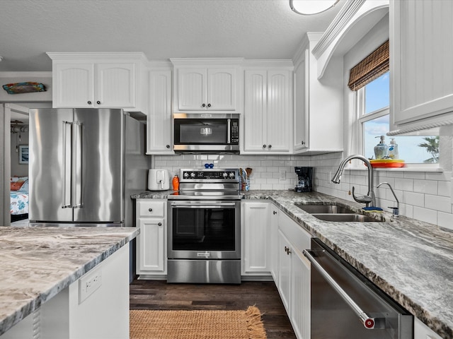 kitchen with light stone countertops, dark hardwood / wood-style flooring, stainless steel appliances, sink, and white cabinetry