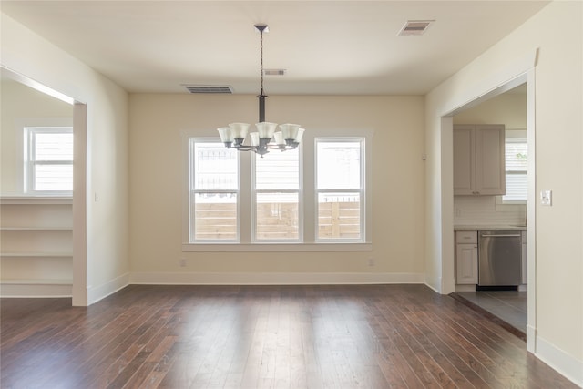 unfurnished dining area featuring plenty of natural light, dark wood-type flooring, and a chandelier