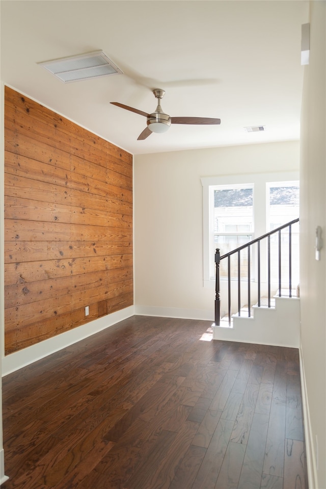 unfurnished room with wooden walls, dark hardwood / wood-style floors, and ceiling fan