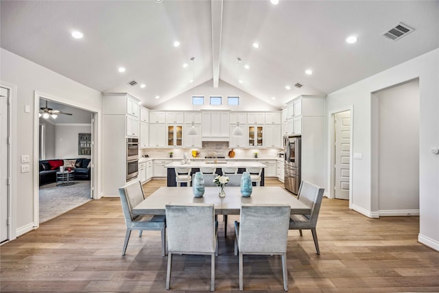 dining area with high vaulted ceiling, sink, ceiling fan, light hardwood / wood-style floors, and beam ceiling