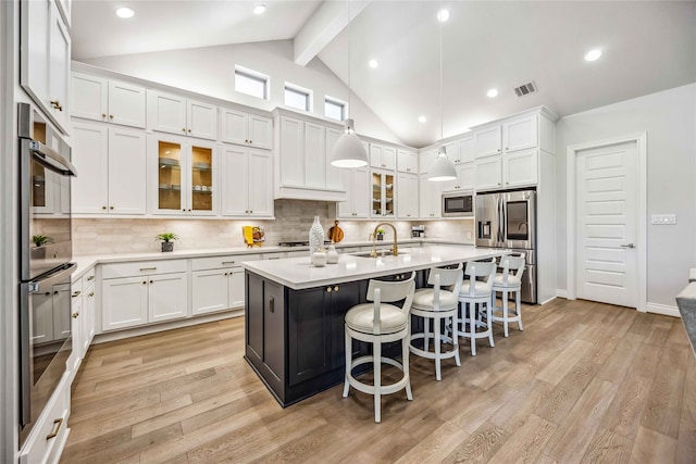 kitchen featuring a kitchen bar, sink, appliances with stainless steel finishes, an island with sink, and white cabinets