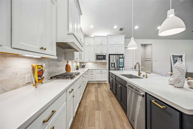 kitchen featuring white cabinetry, sink, decorative light fixtures, and stainless steel appliances