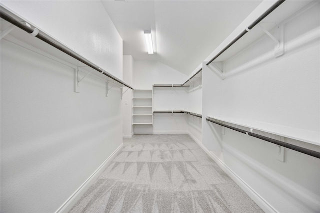 walk in closet featuring lofted ceiling and light colored carpet