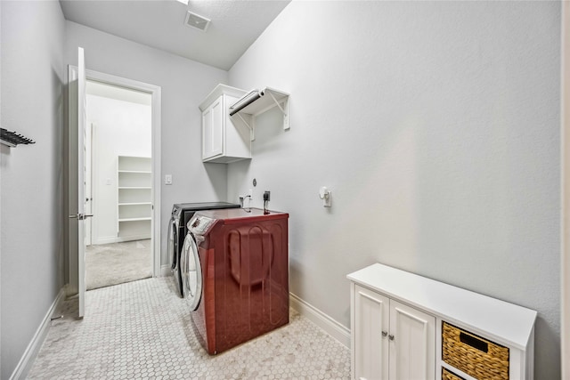 clothes washing area featuring independent washer and dryer and cabinets